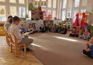 Wolontariusze czytają książkę dzieciom