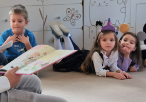 Wolontariusze czytają książkę dzieciom