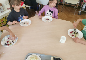 dzieci jedzą owsiankę z wybranymi przez siebie dodatkami