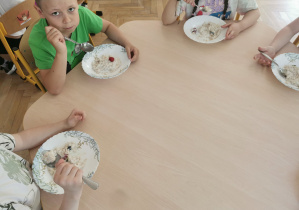 dzieci jedzą owsiankę z wybranymi przez siebie dodatkami