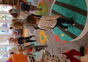 Dzieci maszerują po dywanie i zbierają papierowe jabłka