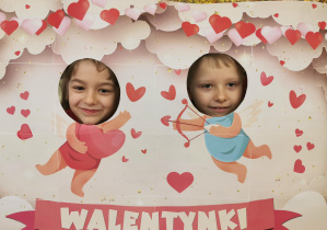 dwoje dzieci w fotobudce, dwa amorki w tle, napis walentynki 11