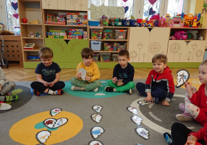 Dzieci siedzą na dywanie i szukają połówek serc