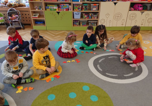 Dzieci siedzą na dywanie i liczą seduszka