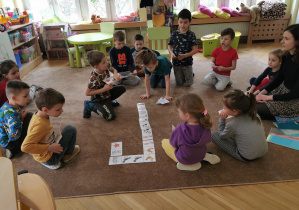 dzieci układają domino obrazkowe na dywanie