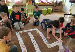 dzieci układają domino obrazkowe na dywanie