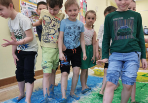 kilkoro dzieci pokazuje ubrudzone farbą stopy