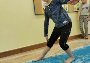 chłopiec chodzi po tkanienie umoczonymi w niebieskiej farbie bosymi stopami