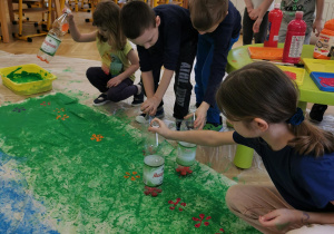 kilkoro dzieci robi stemple w kształcie kwiatków używając plastikowych butelek