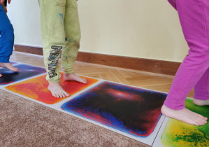 zbliżenie na bose stopy, które chodzą po kolorowych planszach sensorycznych