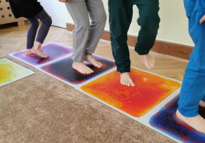zbliżenie na bose stopy, które chodzą po kolorowych planszach sensorycznych