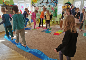 dzieci chodzą po torze sensorycznym ułożonym na dywanie w sali