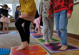 kilkoro dzieci chodzą po kolorowych planszach sensorycznych