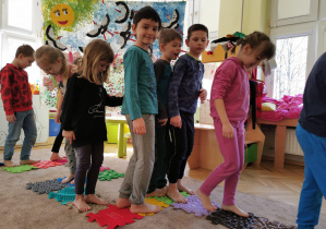 dzieci chodzą po puzzlach sensorycznych ułożonym na dywanie w sali