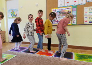 dzieci chodzą po planszach sensorycznych ułożonym na dywanie w sali