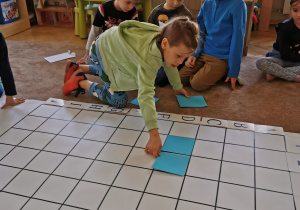 chłopiec układa niebieski kwadrat na planszy do kodowania