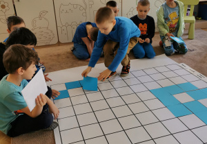 chłopiec układa niebieski kwadrat na planszy do kodowania