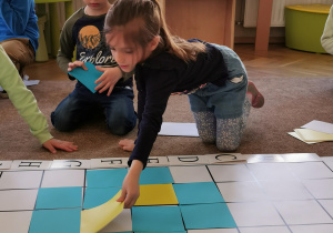 dziewczynka układa niebieski kwadrat na planszy do kodowania