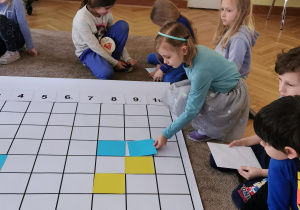 dziewczynka układa niebieski kwadrat na planszy do kodowania