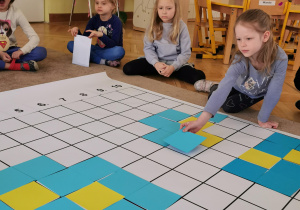 dziewczynka układa niebieski kwadrat na planszy do kodowania
