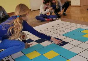 dziewczynka układa granatowy kwadrat na planszy do kodowania