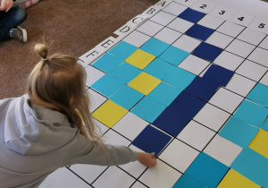 dziewczynka układa granatowy kwadrat na planszy do kodowania