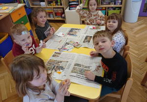 Dzieci siedzą przy stolikach i kolorują kwiatki