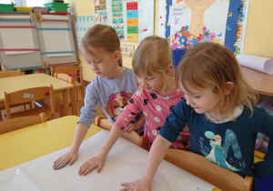 Dzieci odbijają dłoń pomalowaną farbą na szablonie motylka