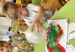Chłopiec stempluje szablon zajączka balonem umoczonym w farbie