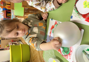 Dziewczynka stempluje szablon zajączka balonem umoczonym w farbie