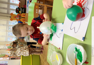 Chłopiec stempluje szablon zajączka balonem umoczonym w farbie