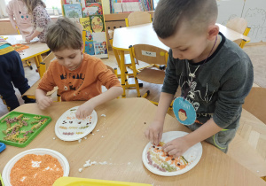 dwaj chłopcy układają kolorowy makaron w masie plastycznej