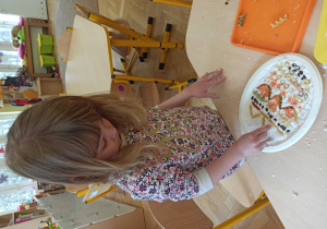 dziewczynka układa kolorowy makaron w masie plastycznej