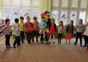dzieci stoją na dywanie i śpiewają piosenkę urodzinową, na środku stoi jubilat