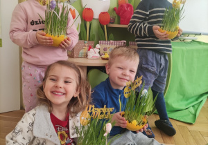 Dzieci pozują do zdjęcia z trawką Wielkanocną.