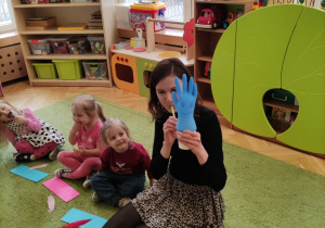 Pani Ilona prezentuje dzieciom ćwiczenie logopedyczne.