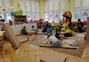dzieci pracują na dywanie w sali majsterkując z surowców wtórnych