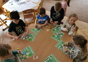 dzieci uzupełniają kartę wyzwań Teodora siedząc przy stoliku