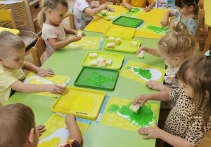 dzieci stemplują ilustrację gruszki gąbką umoczoną w farbie