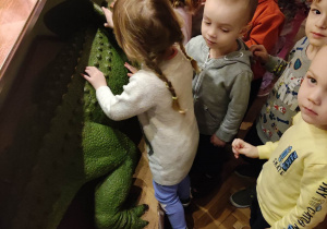 Dzieci głaszczą dinozaura.