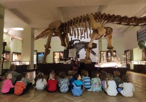 Dzieci słuchają ciekawostek o życiu dinozaurów.