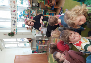 Pani Ola pokazuje ilustrację z książki dzieciom siedzącym przed nią