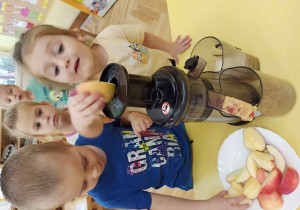 Dzieci wyciskają sok z jabłek.