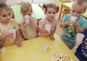 Dzieci piją sok z jabłek własnoręcznie wyciśnięty.