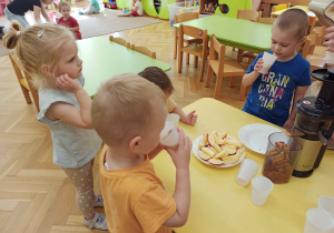 Dzieci piją sok z jabłek własnoręcznie wyciśnięty.