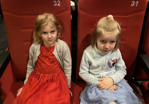 dwie dziewczynki siedzą w fotelach i czekają na film