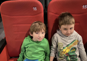 dwaj chłopcy siedzą w fotelach i czekają na film