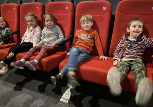 dzieci siedzą w fotelach i czekają na film