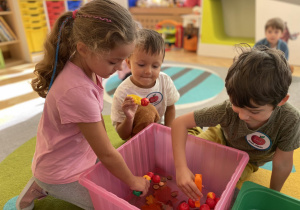 Dzieci chwytają pesetą jabłka z pojemnika z wodą