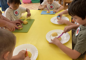 Dzieci siedzą przy stole i wykleją szablon jabłka